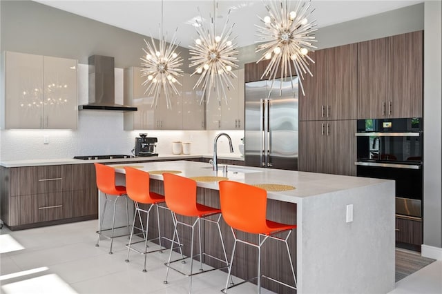 kitchen featuring light countertops, stainless steel built in fridge, modern cabinets, wall chimney range hood, and decorative backsplash