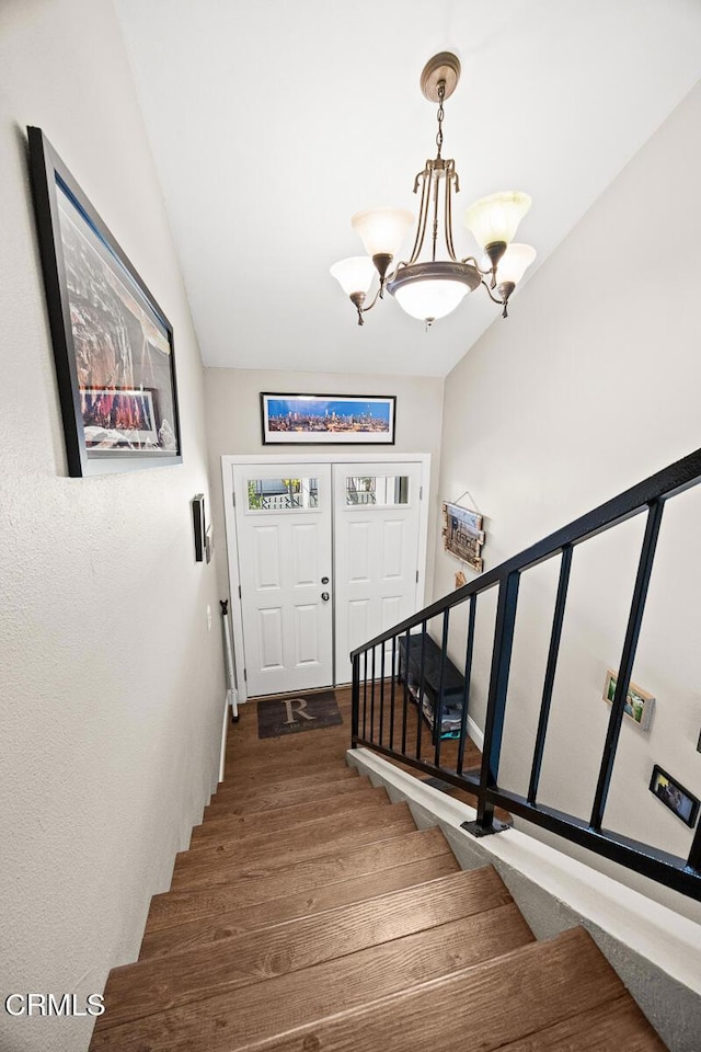 entryway with vaulted ceiling, stairway, wood finished floors, and a notable chandelier