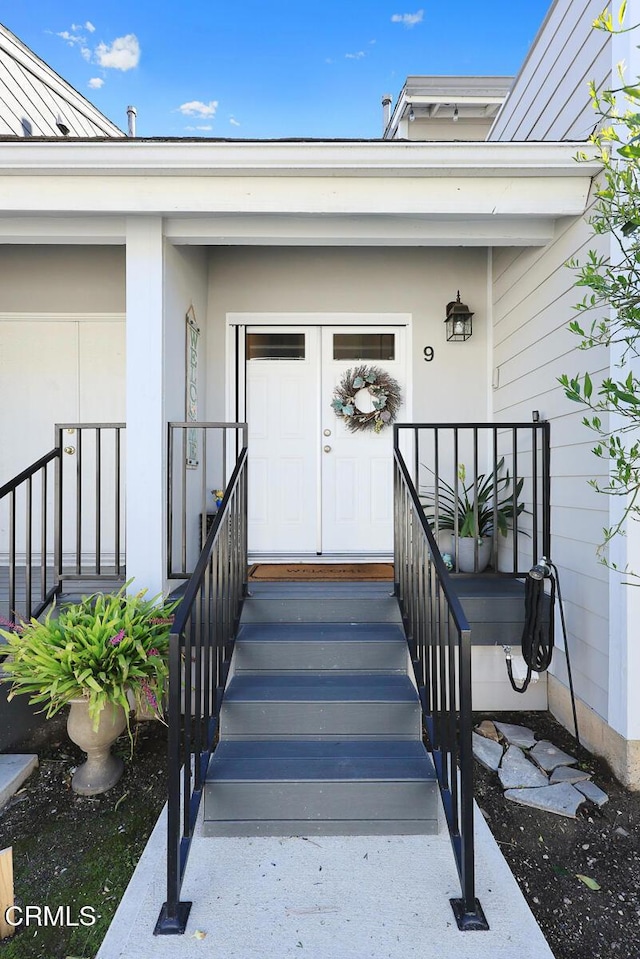 doorway to property with a porch, a standing seam roof, and metal roof