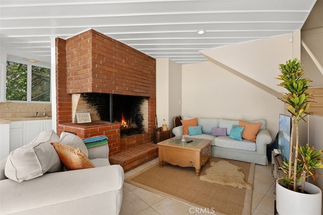 living room with a brick fireplace and light tile patterned flooring