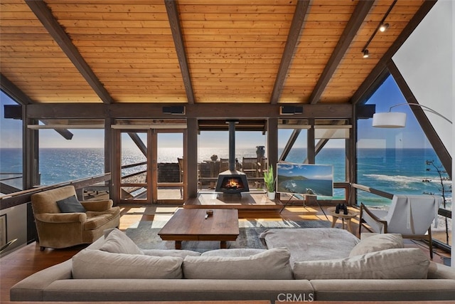 sunroom / solarium with lofted ceiling with beams, wood ceiling, a water view, and a wood stove