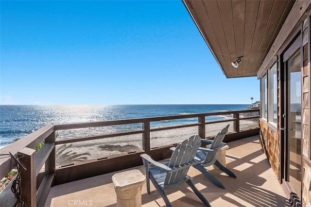 balcony featuring a view of the beach and a water view