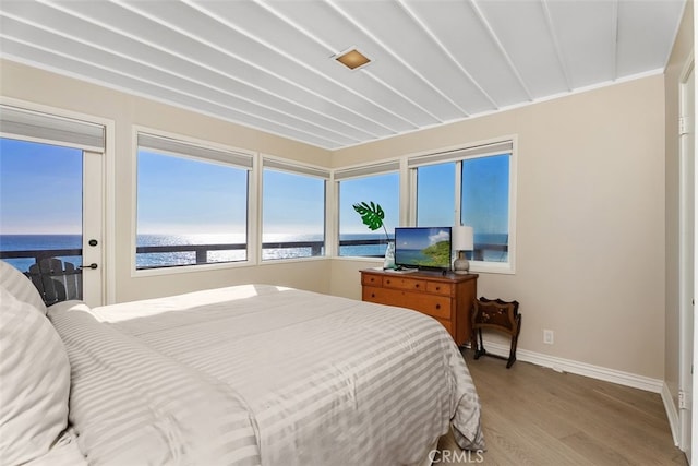 bedroom featuring a water view, baseboards, and wood finished floors