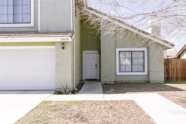 entrance to property featuring fence and stucco siding