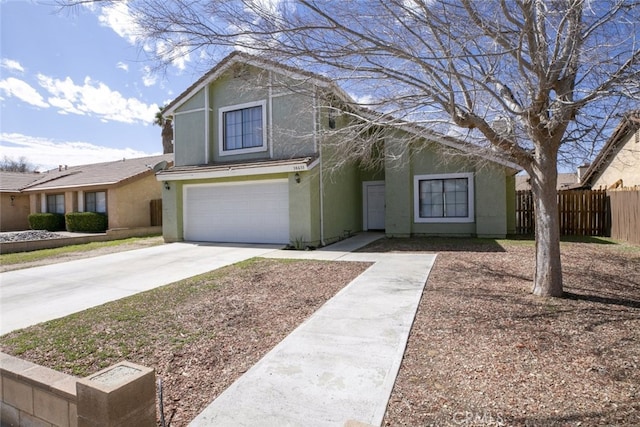 traditional-style house with a garage, concrete driveway, fence, and stucco siding