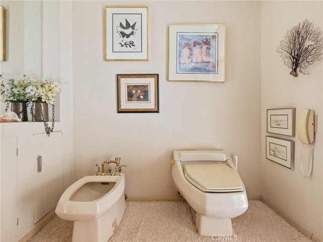 bathroom with a bidet, toilet, and baseboards