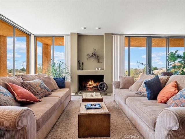 living area with a warm lit fireplace, floor to ceiling windows, and a wealth of natural light