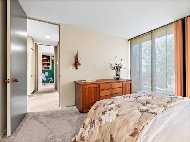 bedroom with a wall of windows and light colored carpet