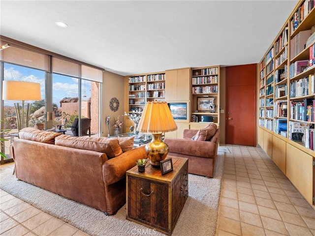 living area featuring wall of books, built in shelves, floor to ceiling windows, and light tile patterned flooring