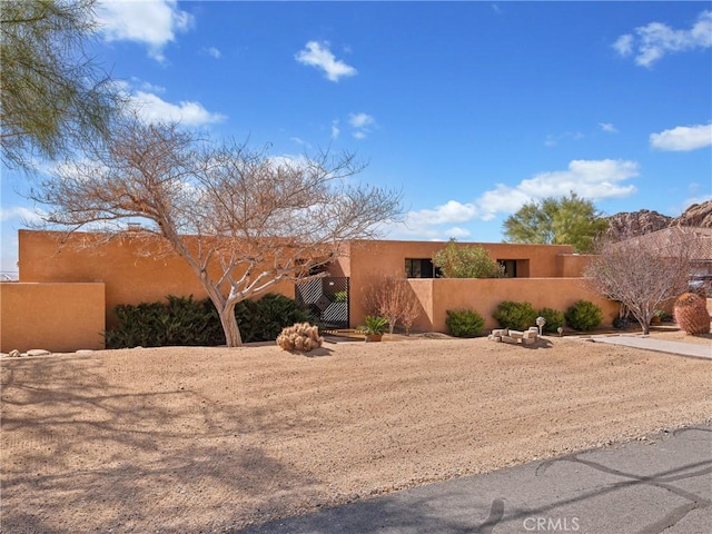 southwest-style home featuring a fenced front yard, a gate, and stucco siding