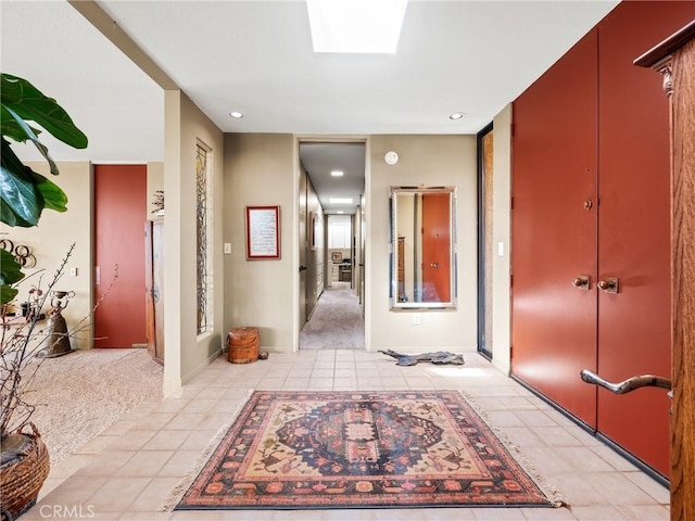 hall with light tile patterned floors, a skylight, light carpet, and recessed lighting