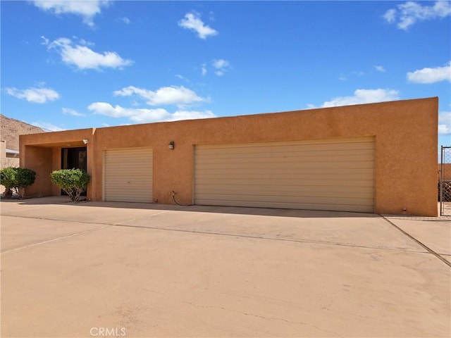 view of front facade with concrete driveway, an attached garage, and stucco siding