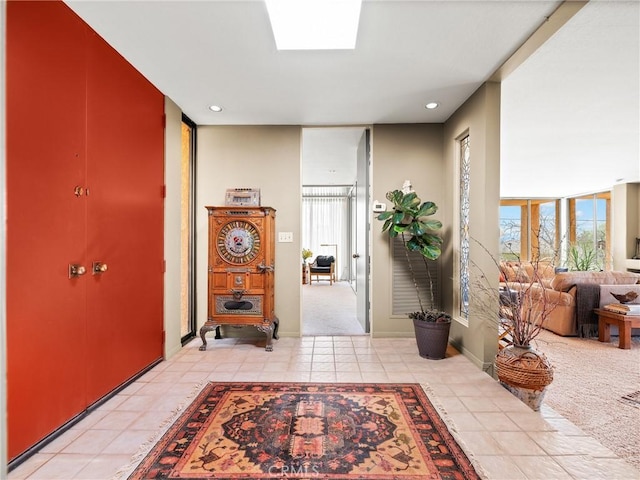 hall featuring a skylight, recessed lighting, expansive windows, light carpet, and light tile patterned flooring