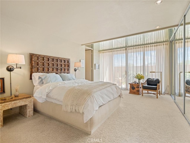 bedroom with carpet, access to outside, multiple windows, and a wall of windows