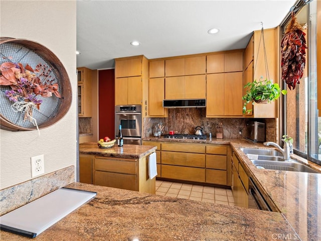 kitchen with light tile patterned floors, under cabinet range hood, stainless steel appliances, a sink, and backsplash