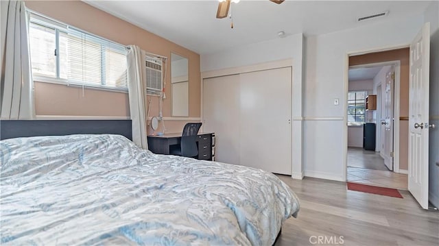 bedroom with a ceiling fan, multiple windows, visible vents, and wood finished floors