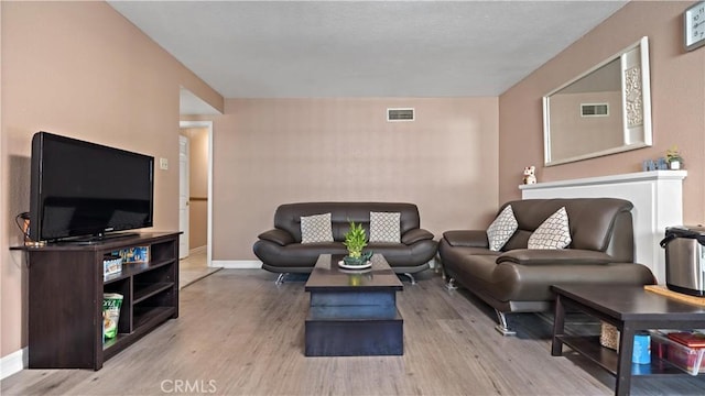 living area with baseboards, visible vents, and wood finished floors