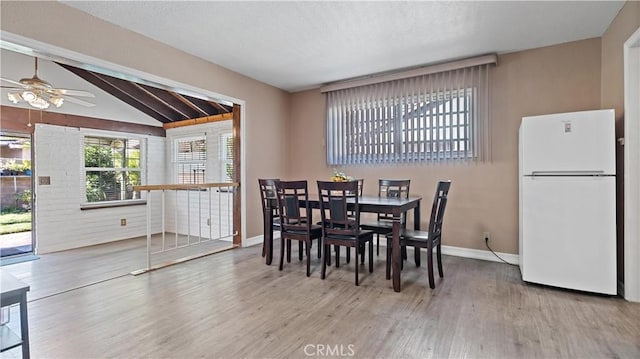 dining area featuring lofted ceiling, ceiling fan, wood finished floors, and baseboards