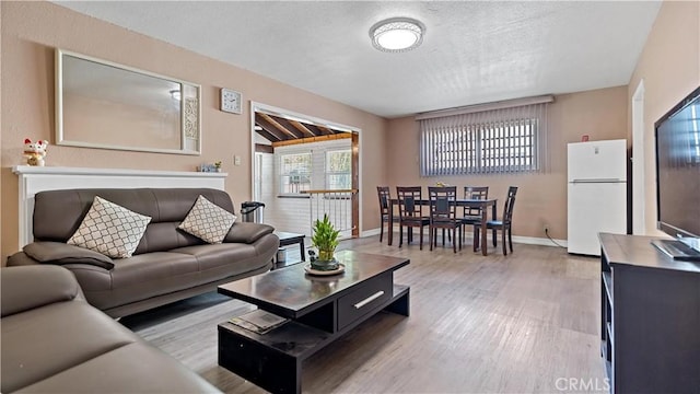 living room featuring light wood-style flooring, baseboards, and a textured ceiling