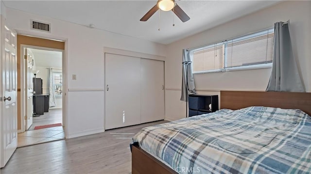 bedroom with light wood-style floors, a closet, visible vents, and ceiling fan