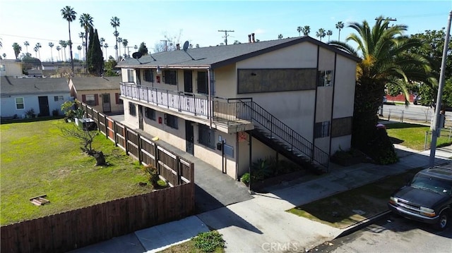 view of front of property featuring stairs, a front yard, and stucco siding