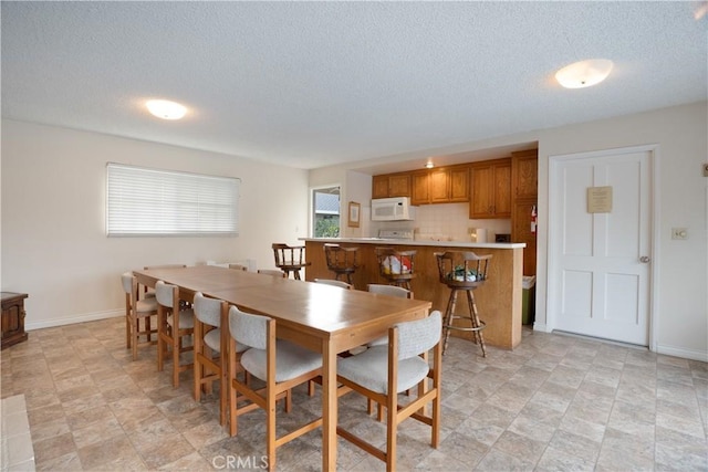 dining room with a textured ceiling and baseboards