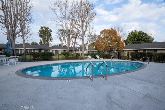 pool with a patio, fence, and a residential view