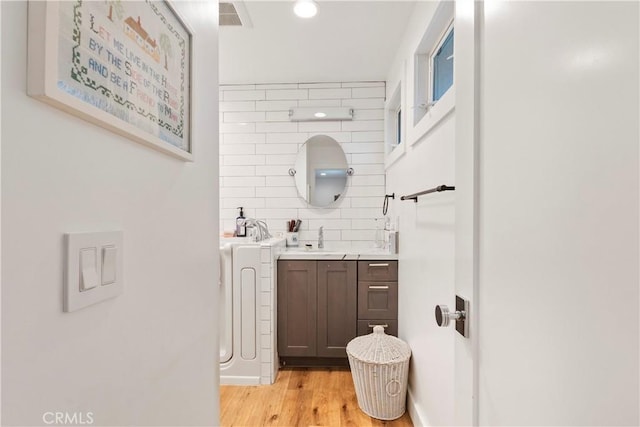 bathroom with tasteful backsplash, visible vents, wood finished floors, vanity, and recessed lighting