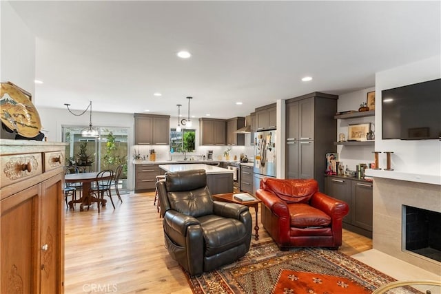 living area with a fireplace with flush hearth, recessed lighting, and light wood finished floors