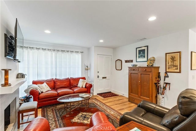 living area with light wood-style flooring, recessed lighting, a fireplace, visible vents, and baseboards