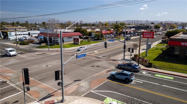 view of road with traffic lights, sidewalks, curbs, street lighting, and traffic signs