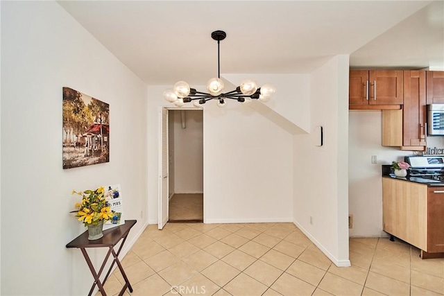 dining area with light tile patterned floors, baseboards, and an inviting chandelier