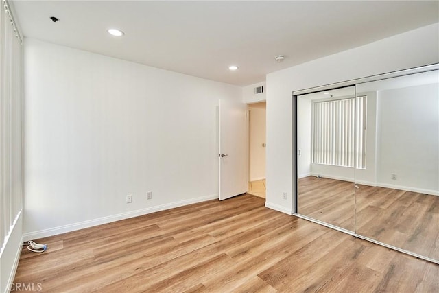 unfurnished bedroom featuring light wood finished floors, baseboards, visible vents, a closet, and recessed lighting