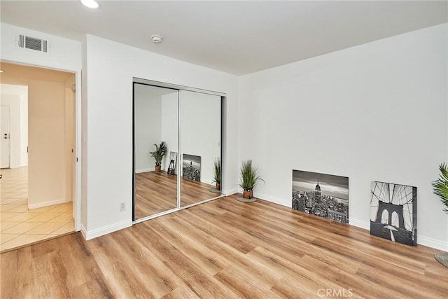 unfurnished bedroom with baseboards, a closet, visible vents, and wood finished floors