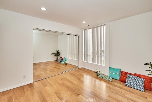 exercise area featuring baseboards, wood finished floors, and recessed lighting