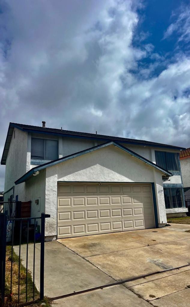 view of side of property with a garage, fence, concrete driveway, and stucco siding