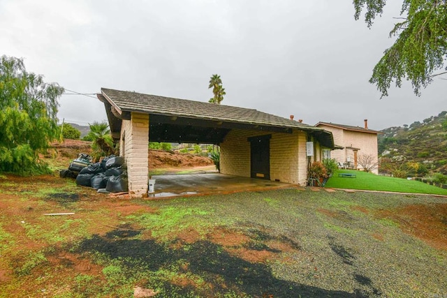 exterior space featuring driveway, a carport, and a front yard