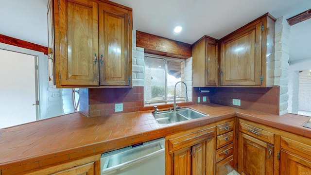 kitchen featuring dishwasher, backsplash, a sink, and brown cabinetry