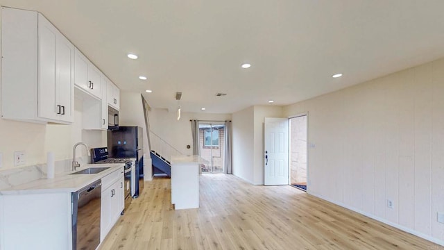 kitchen with black appliances, light wood-style flooring, white cabinetry, and a sink