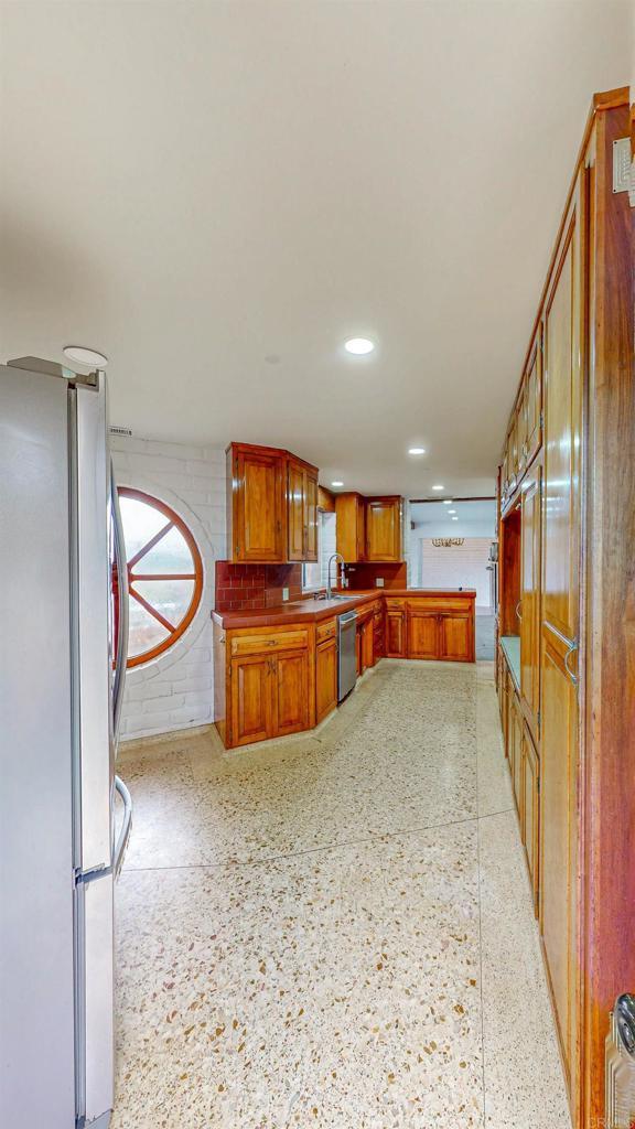 kitchen featuring stainless steel appliances, recessed lighting, brown cabinetry, and light speckled floor