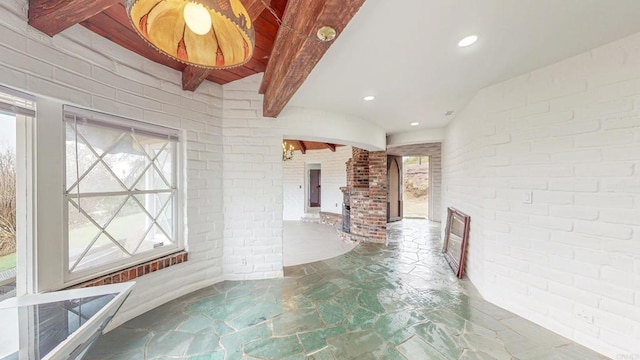 interior space with recessed lighting, brick wall, beam ceiling, and stone finish flooring