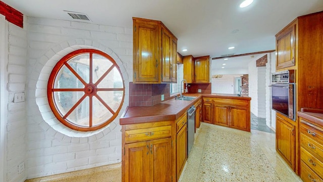 kitchen featuring light speckled floor, stainless steel appliances, a sink, visible vents, and tile counters