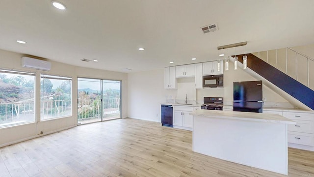 kitchen with a sink, visible vents, light wood-style floors, an AC wall unit, and black appliances