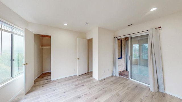 unfurnished bedroom featuring access to exterior, light wood-type flooring, and multiple windows