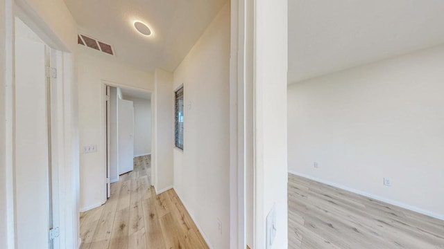 corridor featuring light wood-type flooring, baseboards, and visible vents