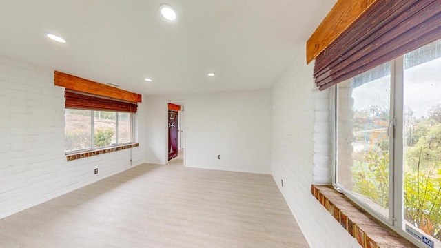 empty room with brick wall, wood finished floors, and recessed lighting