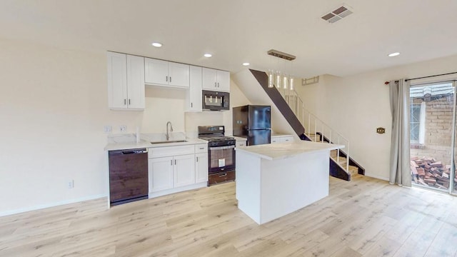 kitchen featuring light wood finished floors, visible vents, white cabinets, black appliances, and a sink