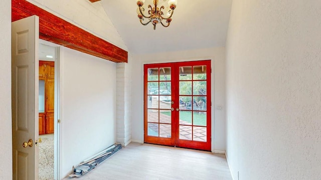 entryway with lofted ceiling, french doors, wood finished floors, and an inviting chandelier