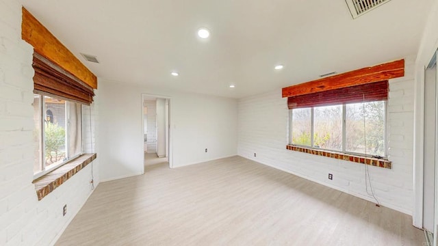 unfurnished room with light wood-type flooring, visible vents, brick wall, and recessed lighting