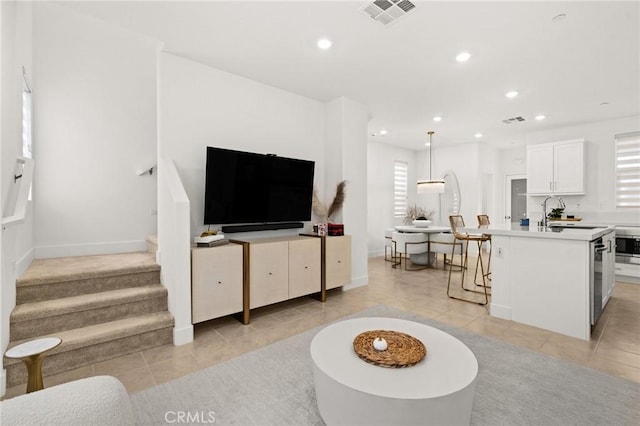 living room featuring recessed lighting, visible vents, light tile patterned flooring, and stairs